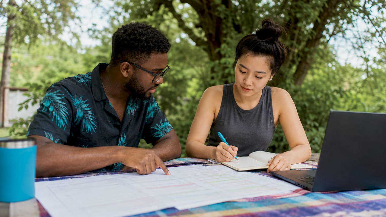 Two developers collaborating over pipeline code printouts
