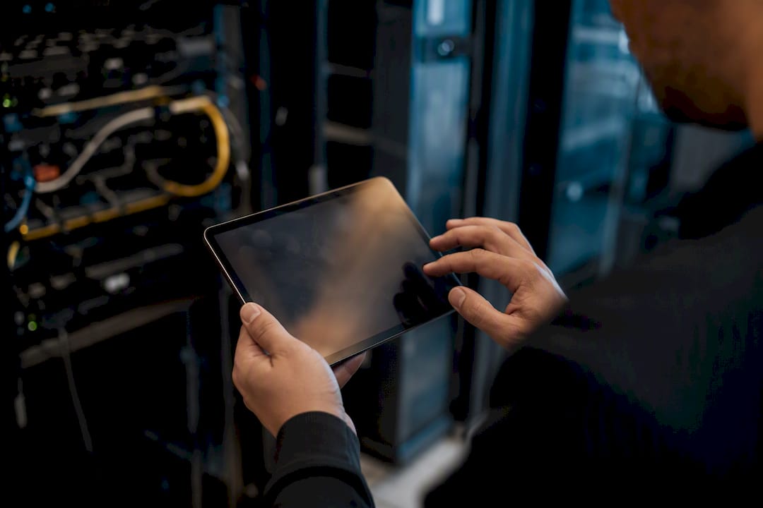 Hands interacting with dark tablet in server area