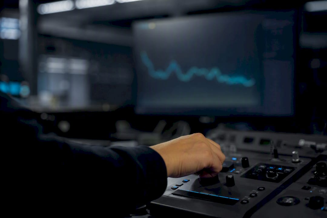 Hand adjusting control near blurred monitoring screen