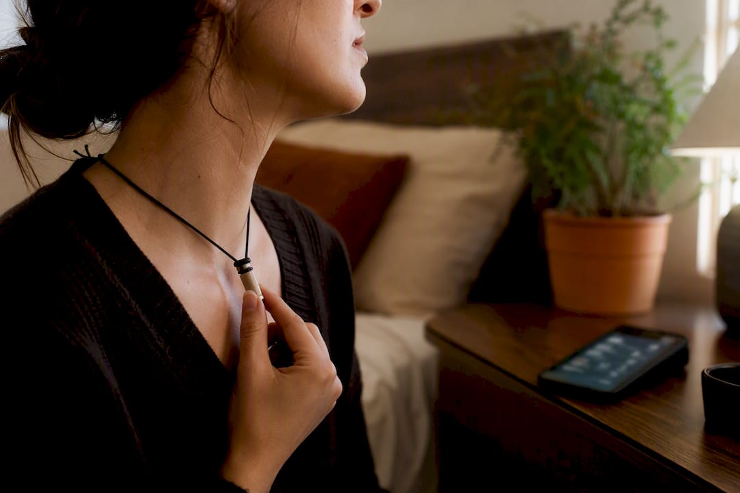 Hand adjusting oral fixation necklace near smartphone