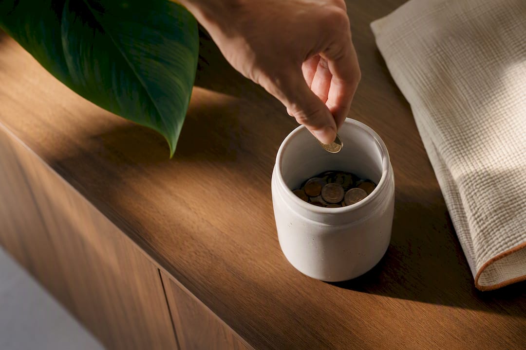 Hand adding coin to progress jar