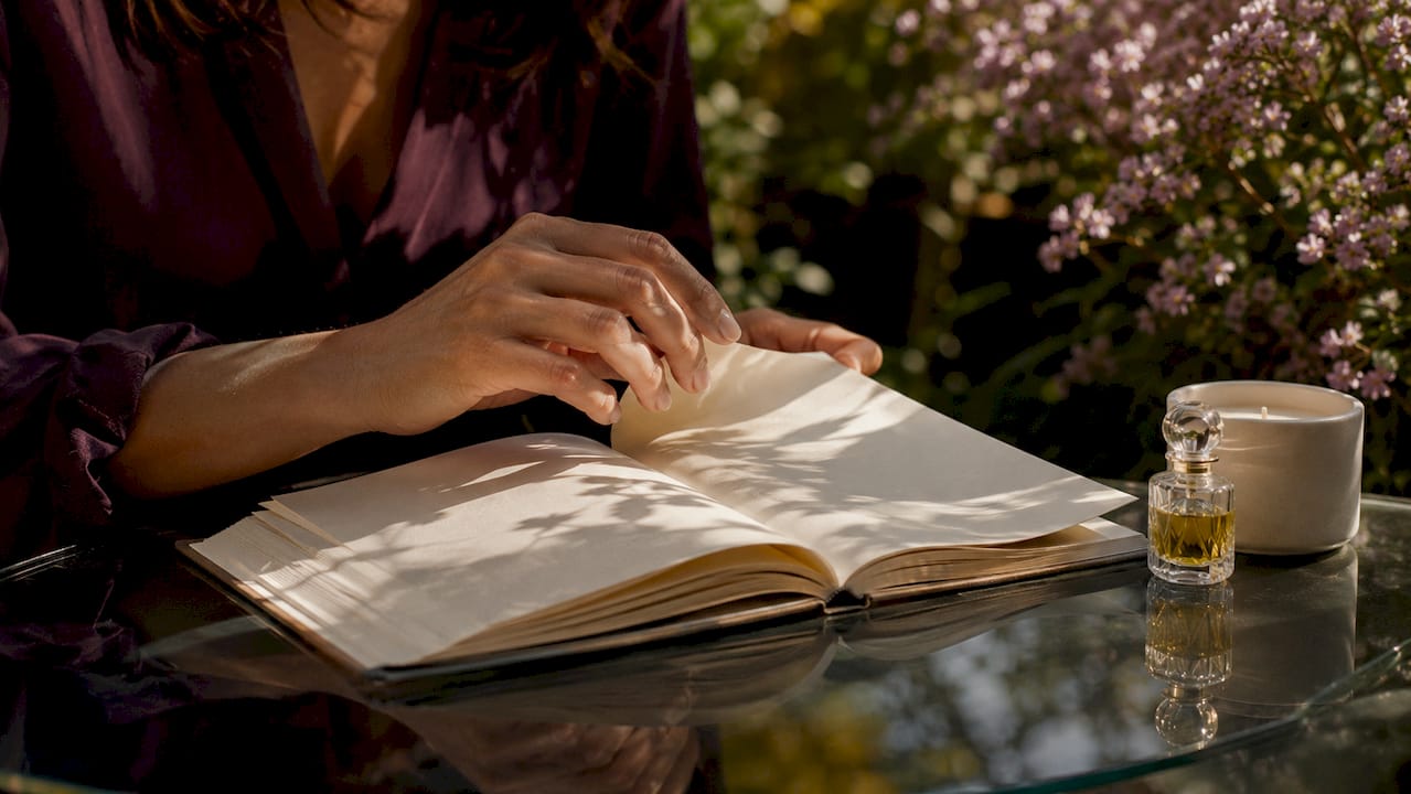 Hands poised to journal with fragrance items nearby