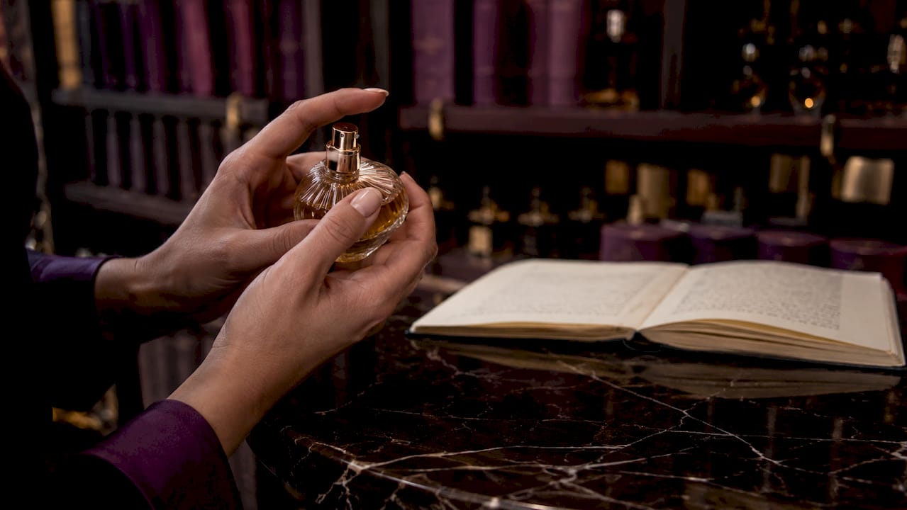 Detalle de unas manos rociando perfume artesanal sobre la piel