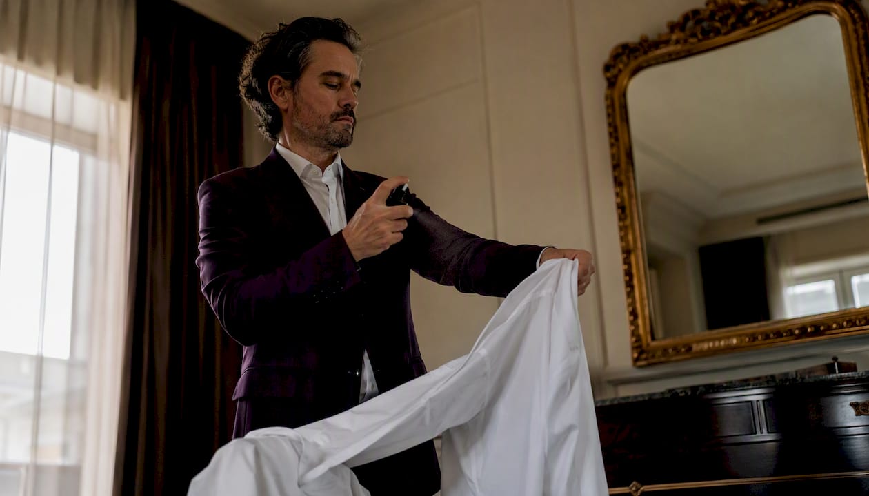 Un hombre se perfuma sobre una camisa blanca