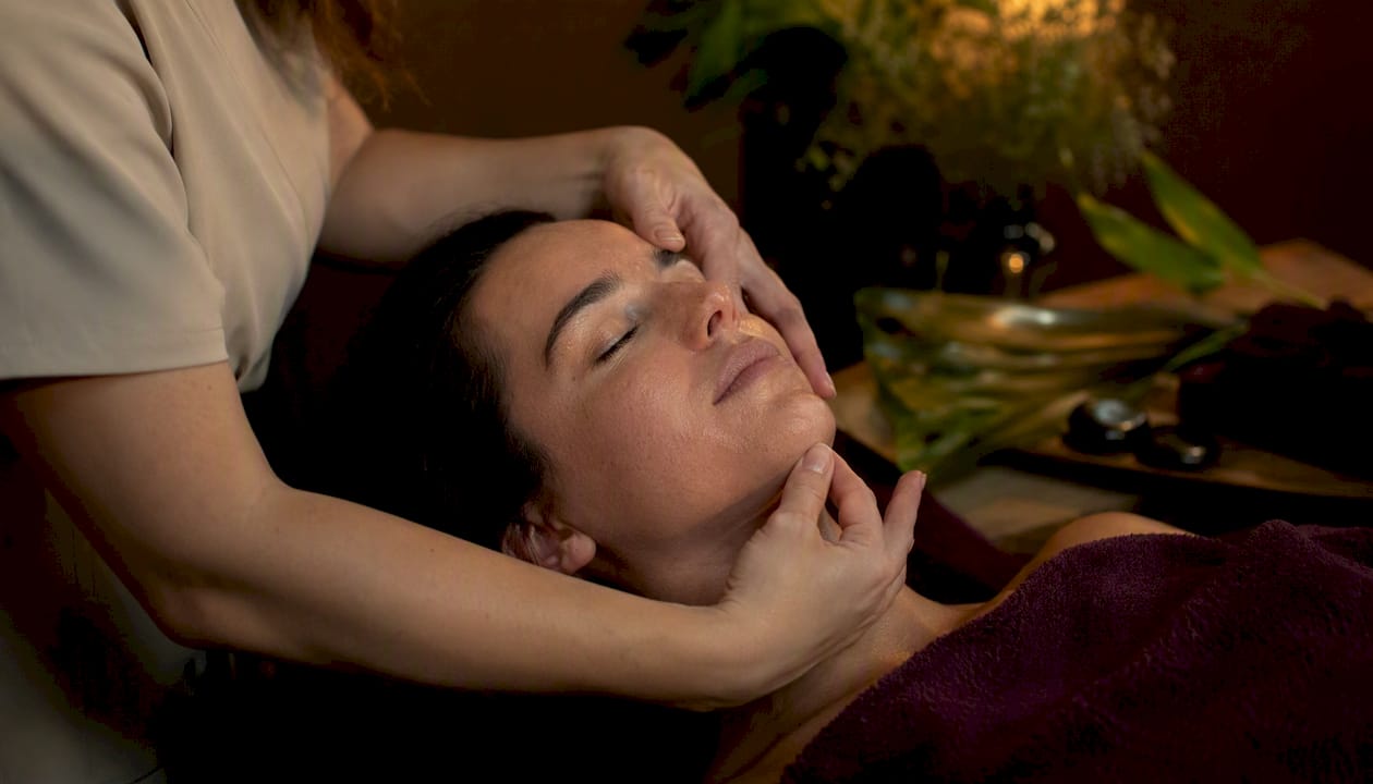 Unas manos deslizan suavemente sobre el rostro, brindando un masaje relajante propio de un tratamiento de belleza.