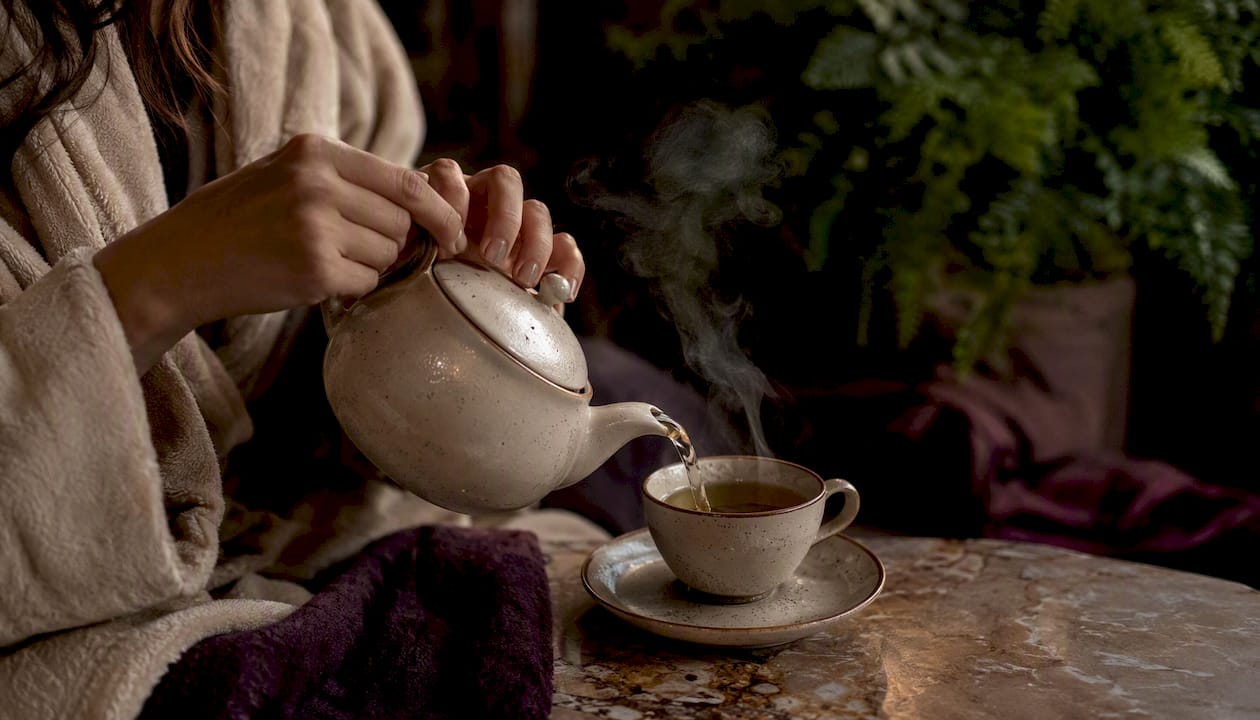 Hands pouring herbal tea in spa environment