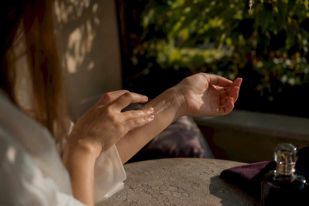 Hand applying moisturizer on wrist for scent layering