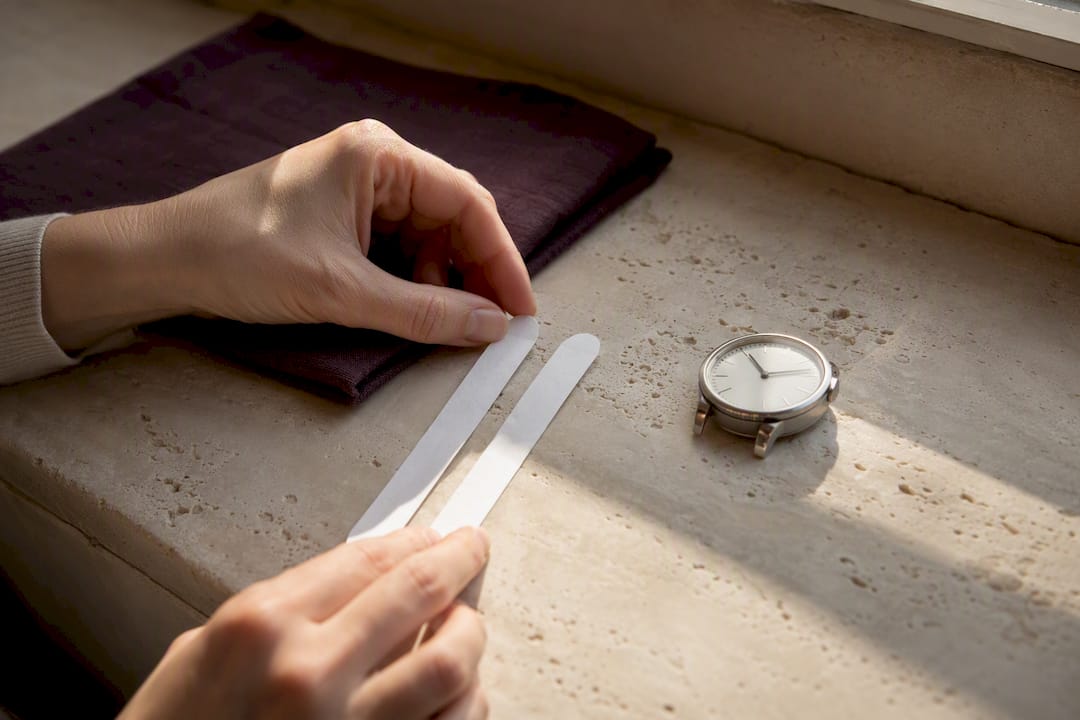 Two perfume strips compared beside analog watch
