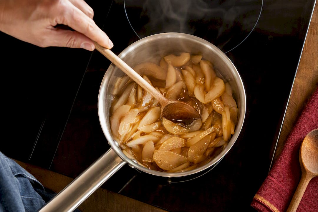 Sliced pears reducing into glossy syrup sauce