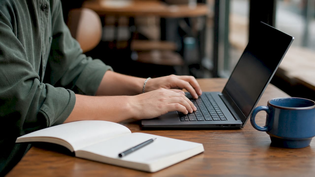 Hands typing with technical security reports on desk