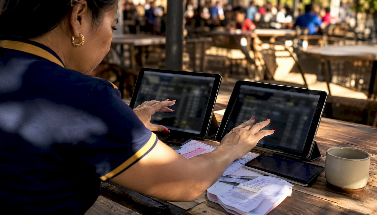 Hands managing multiple betting devices on table