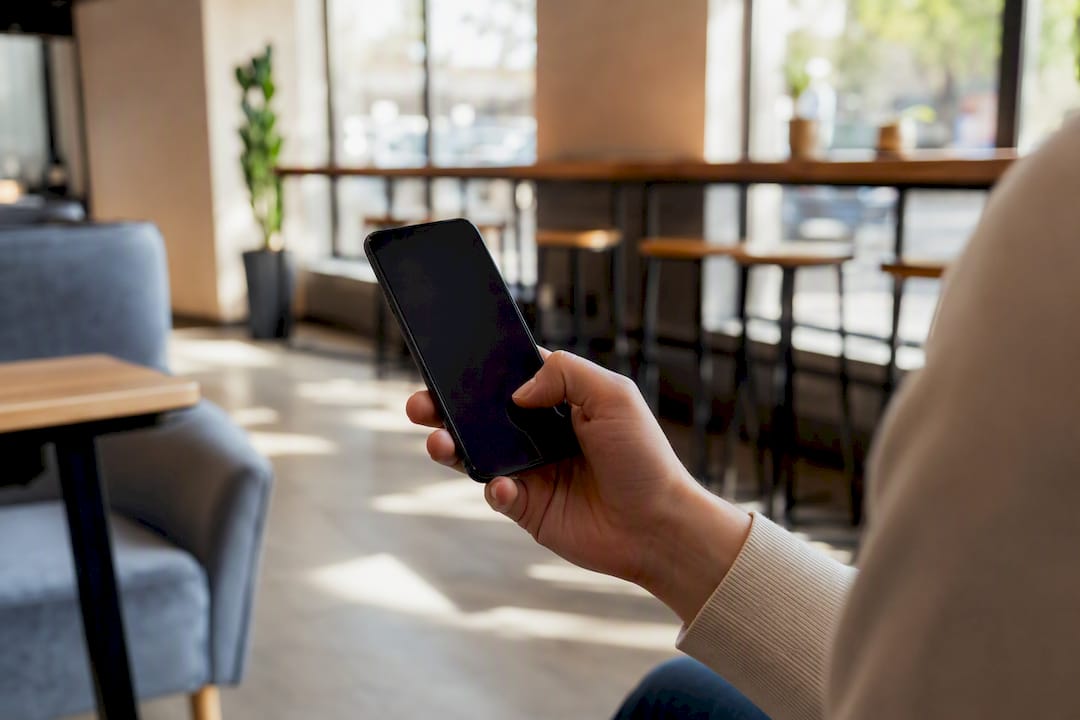 Roka drži pametni telefon, pripravljena na izvedbo denarnega prenosa.