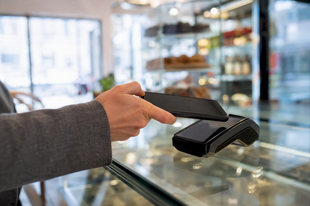 Roka drži telefon za mobilno plačilo