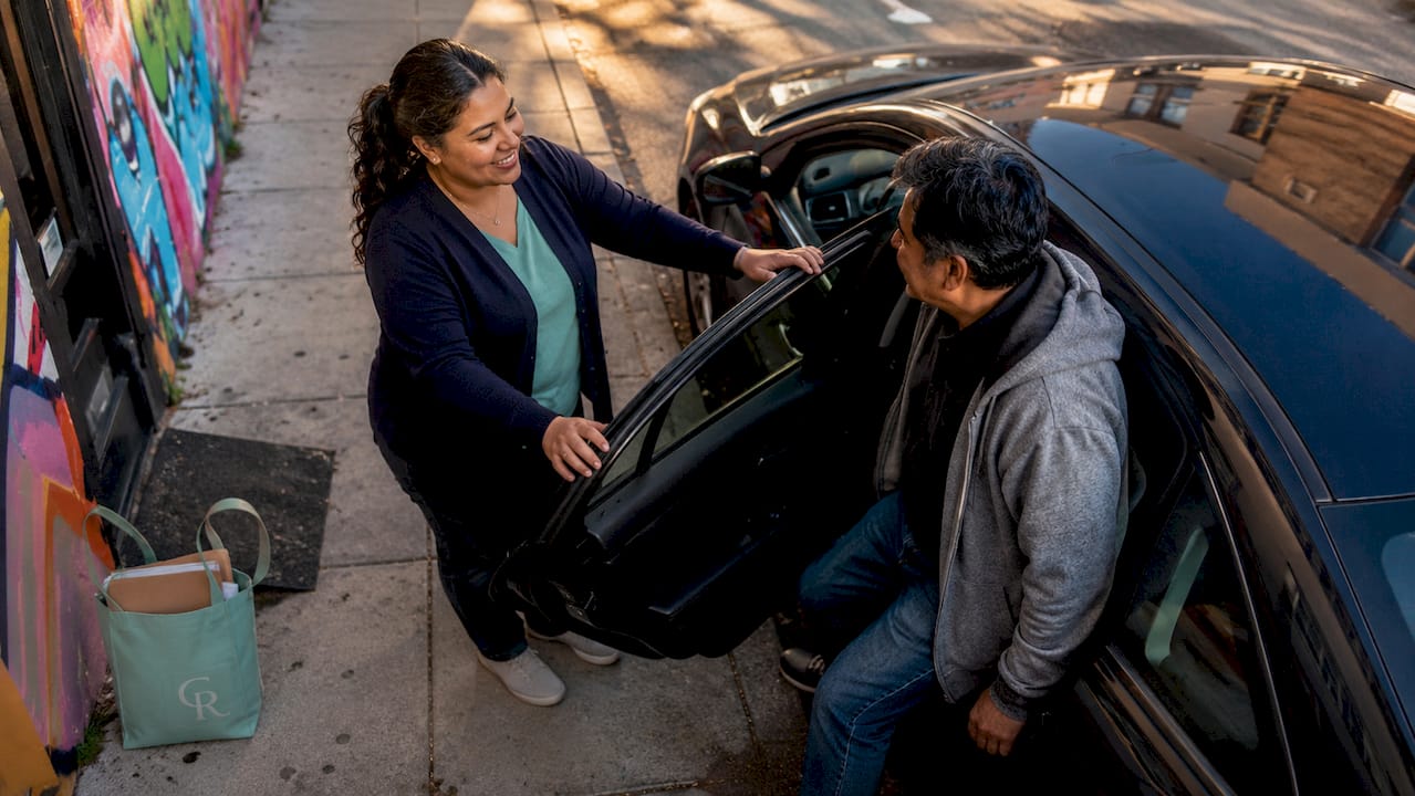 Peer specialist assisting man into car