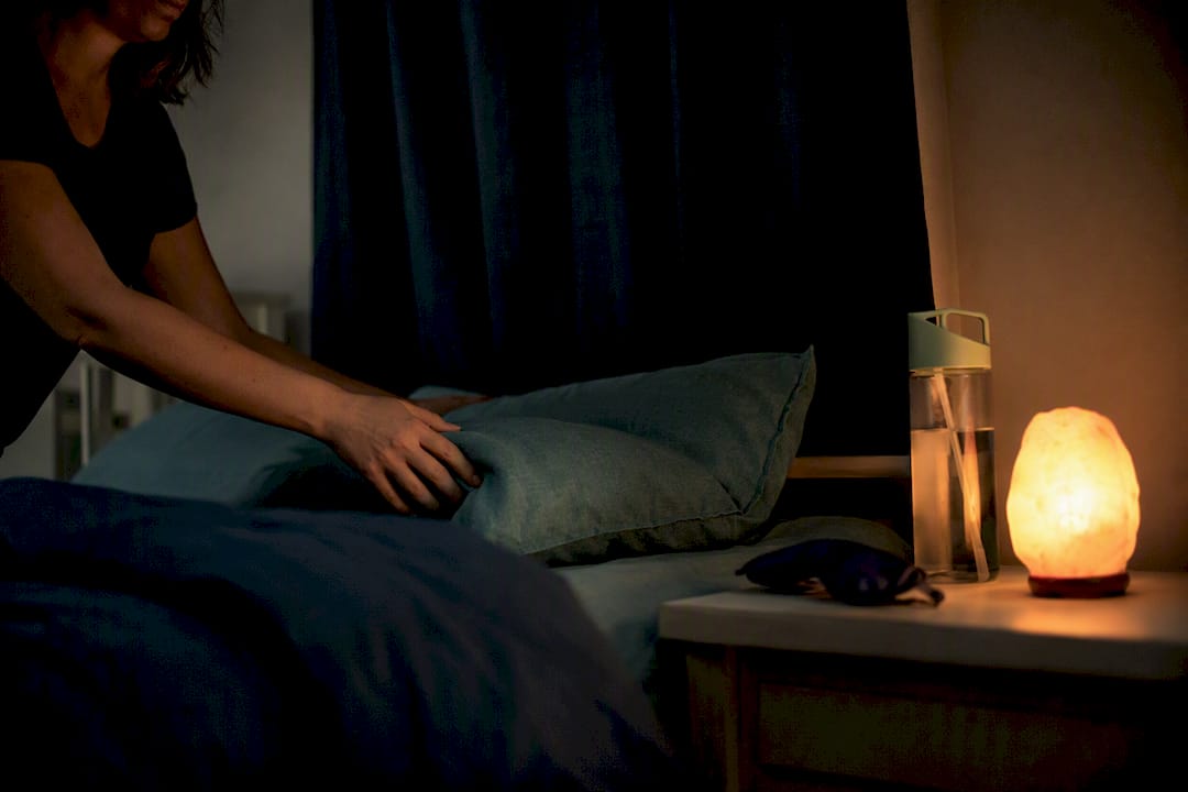 Bedside table with sleep aid items in dim bedroom