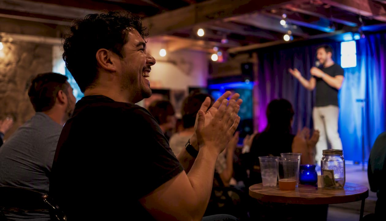 Audience member clapping at local comedy show