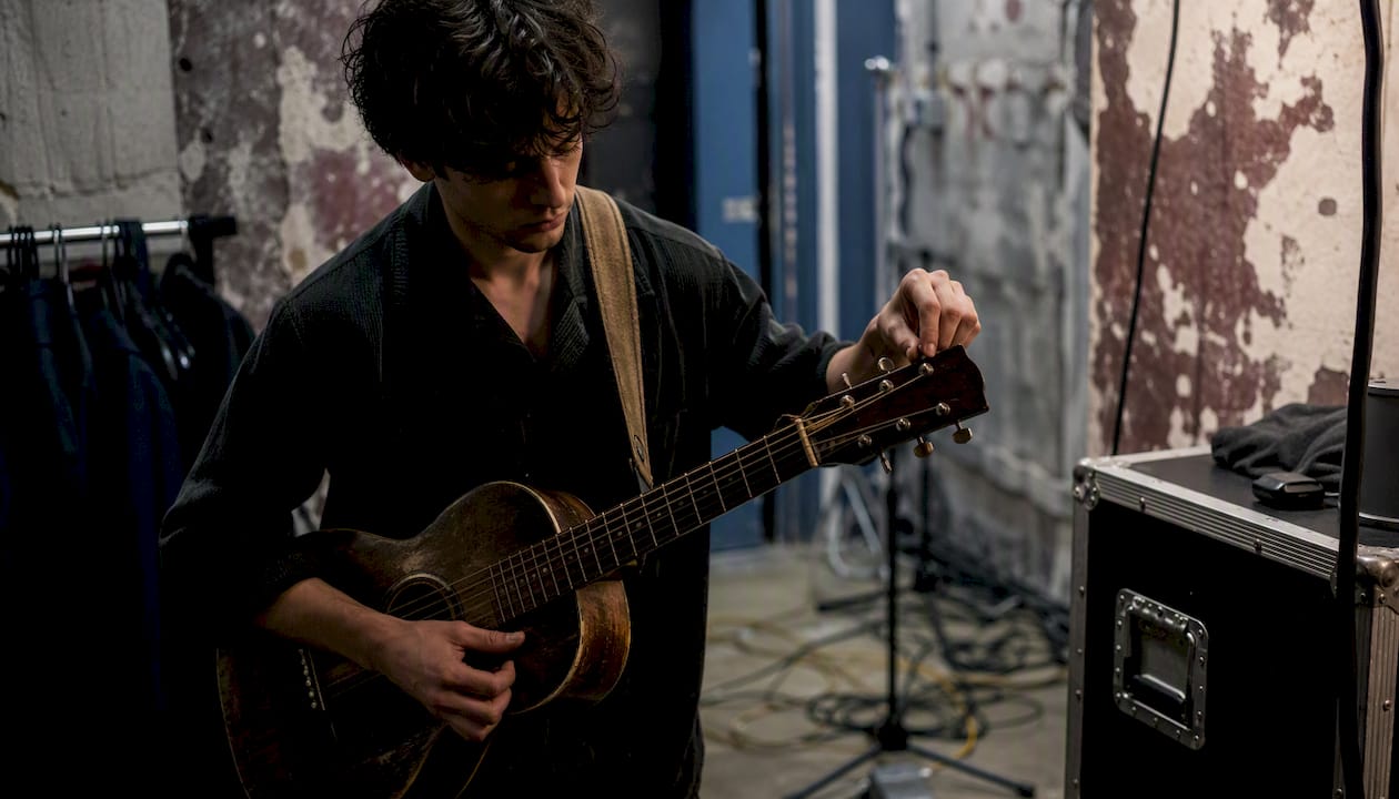 Hands tuning acoustic guitar backstage