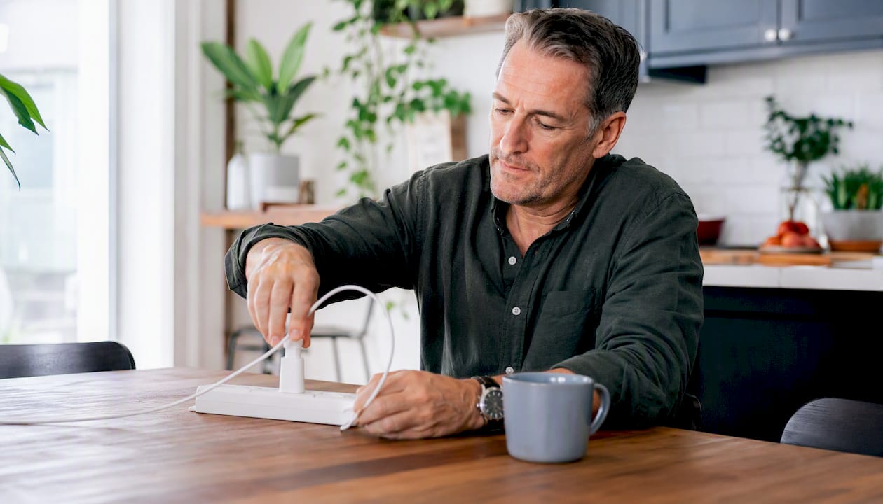 Man plugging phone charger into power strip