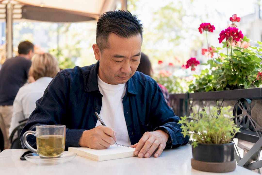 Man writing niche ideas at kitchen table
