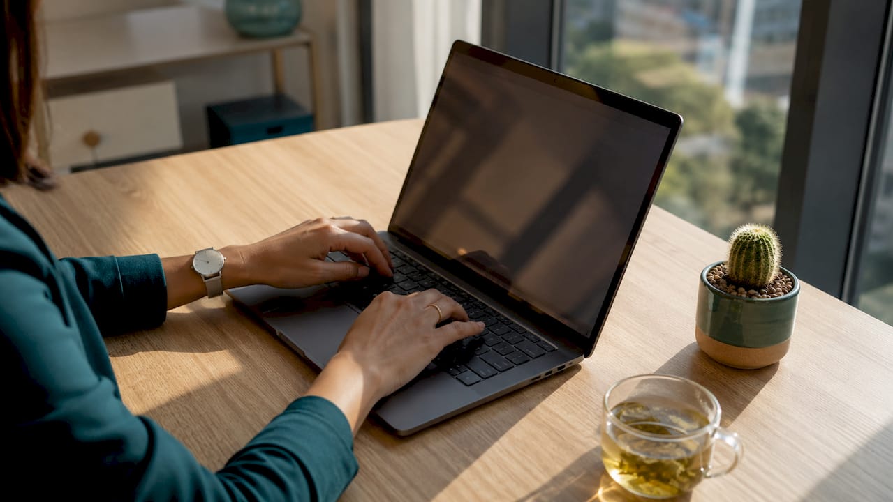 Hands typing on keyboard with laptop and coffee