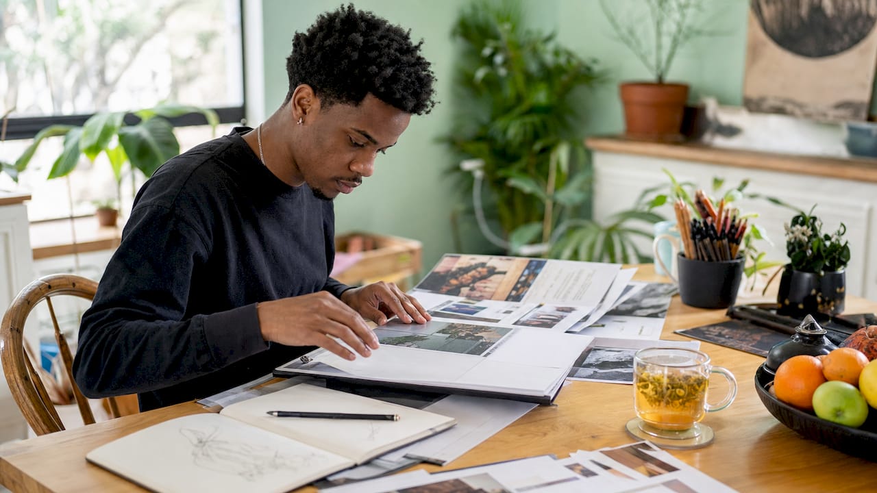 Artist reviewing printed submission portfolio at gallery office