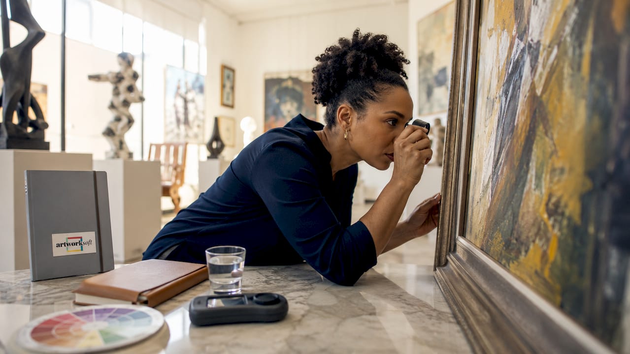 Art appraiser inspecting artwork closely in studio