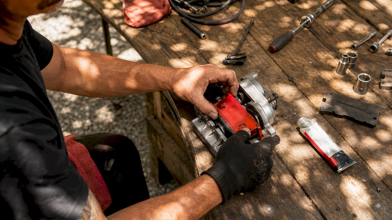 Hands installing red brake pads in garage