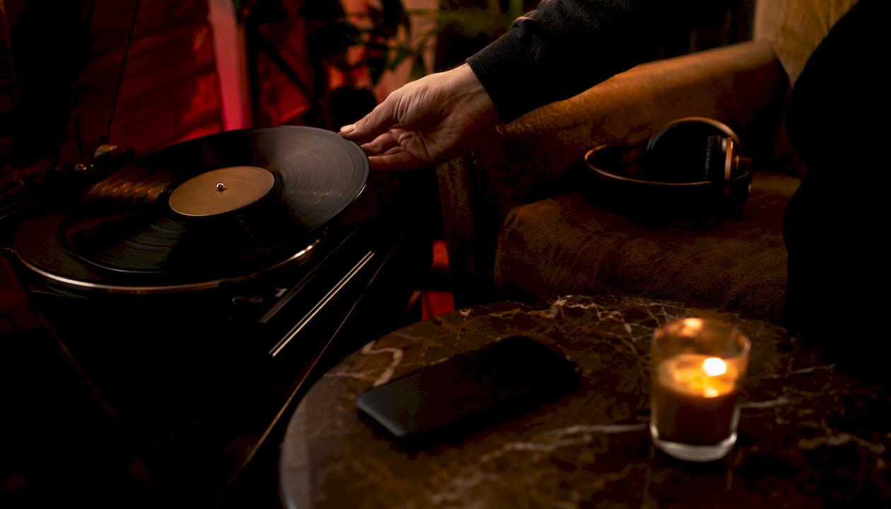 Hand adjusting vinyl turntable at night