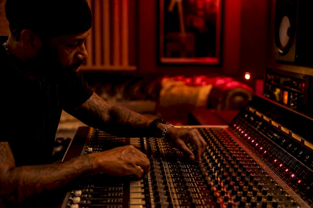 Hands adjusting mixing console in dim studio