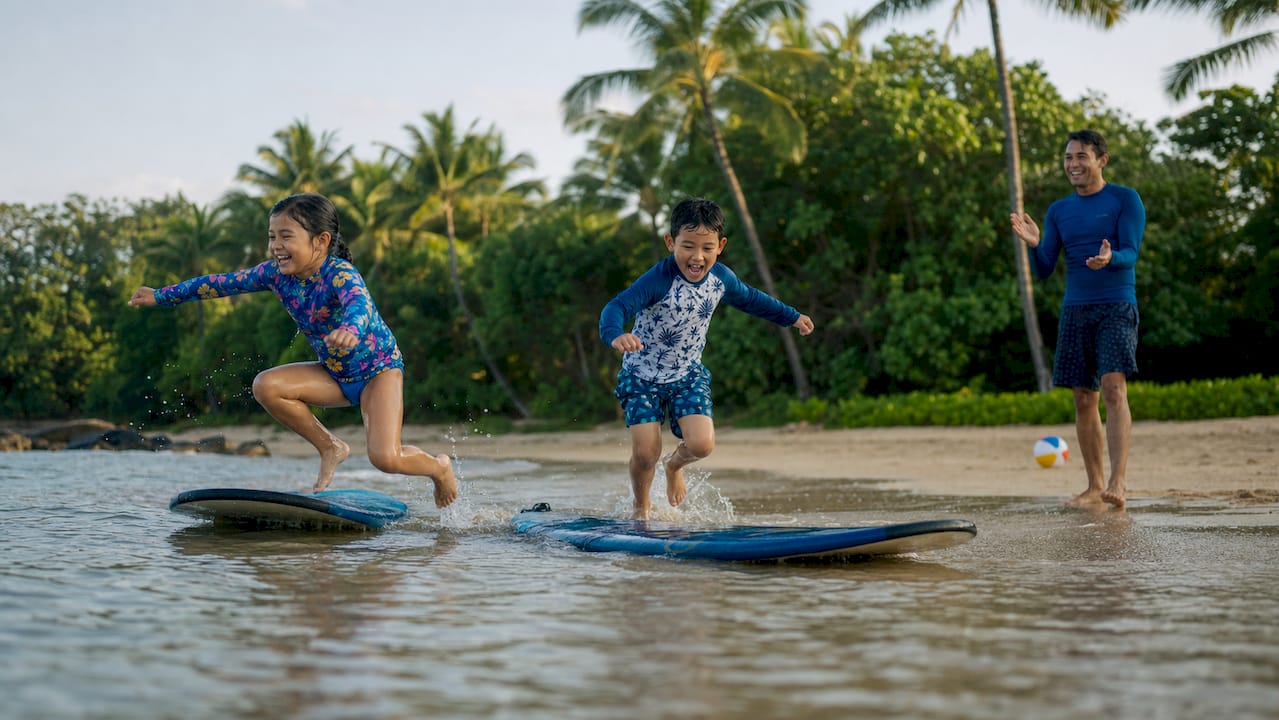 Kids playing and learning surfing in shallow water