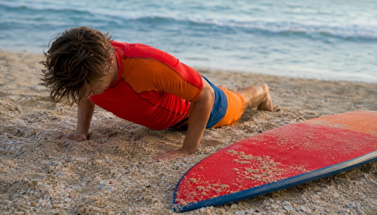 Beginner practicing surf pop-ups on sand