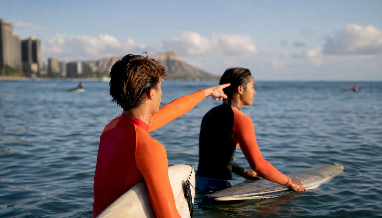 Two surf buddies signaling waves in ocean