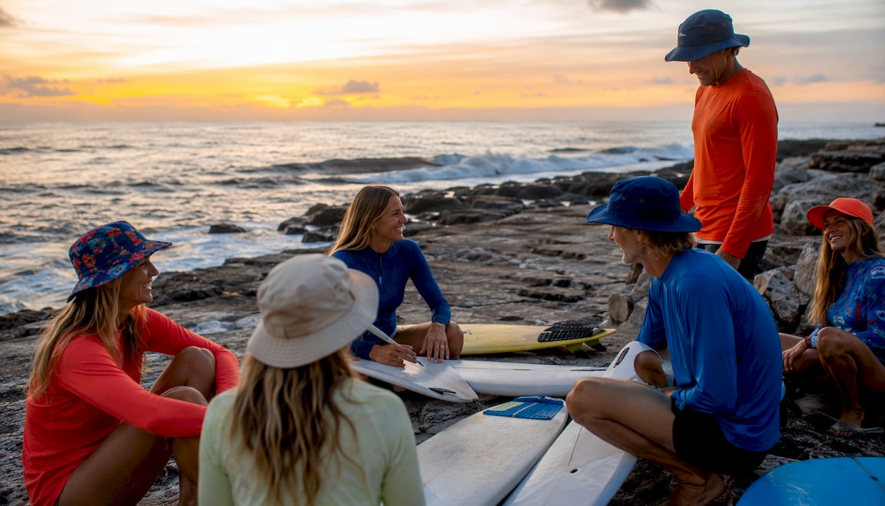 Group of surfers wearing UPF clothing on sunny beach