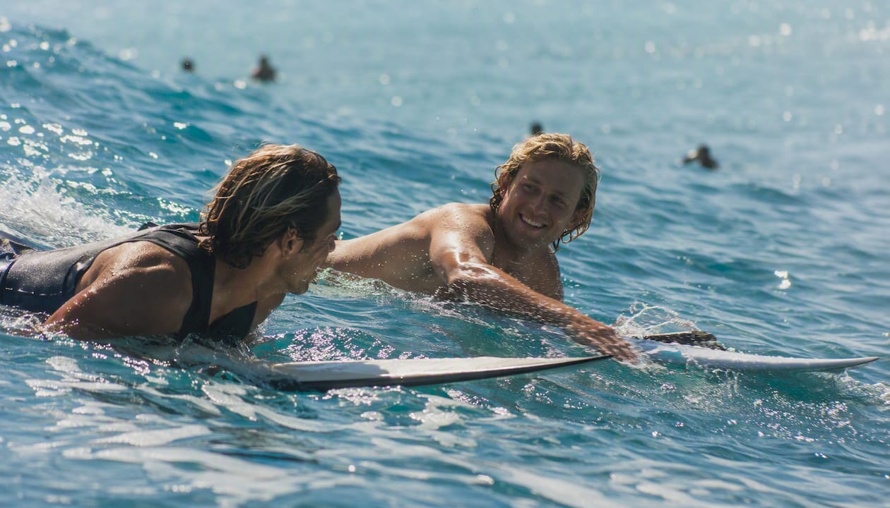 Surfers paddling with nonverbal cues near wave peak