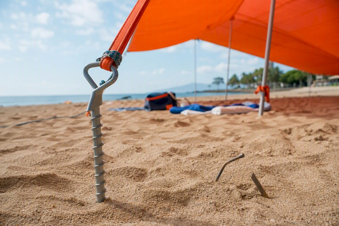 Sand screw anchors securing beach canopy