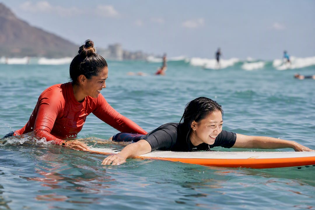 Surf instructor assisting beginner paddling