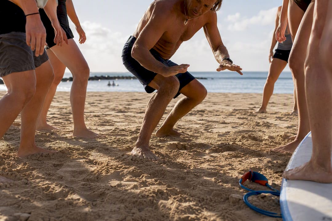 Beginners practicing surf stance on sand