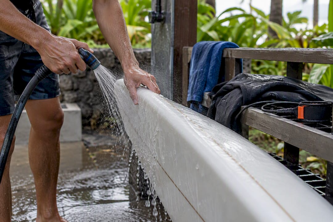 Surfer rinsing board and wetsuit after rain
