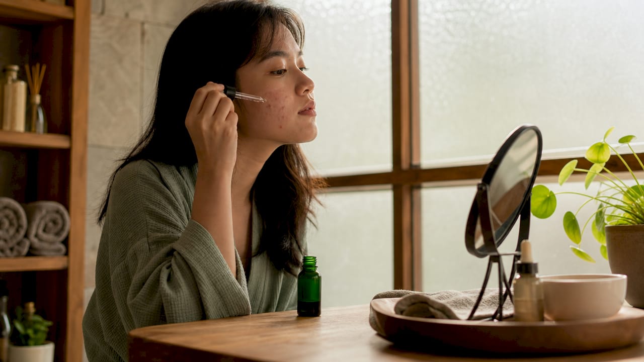 Applying tea tree oil on acne-prone skin