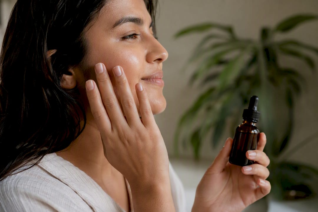 Close-up of hydrated skin and hand with dropper bottle
