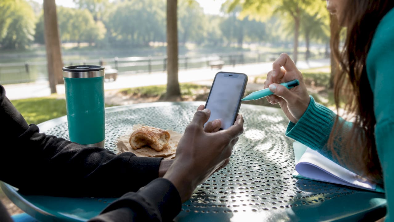 Hands sharing wishlist on smartphone in café setting