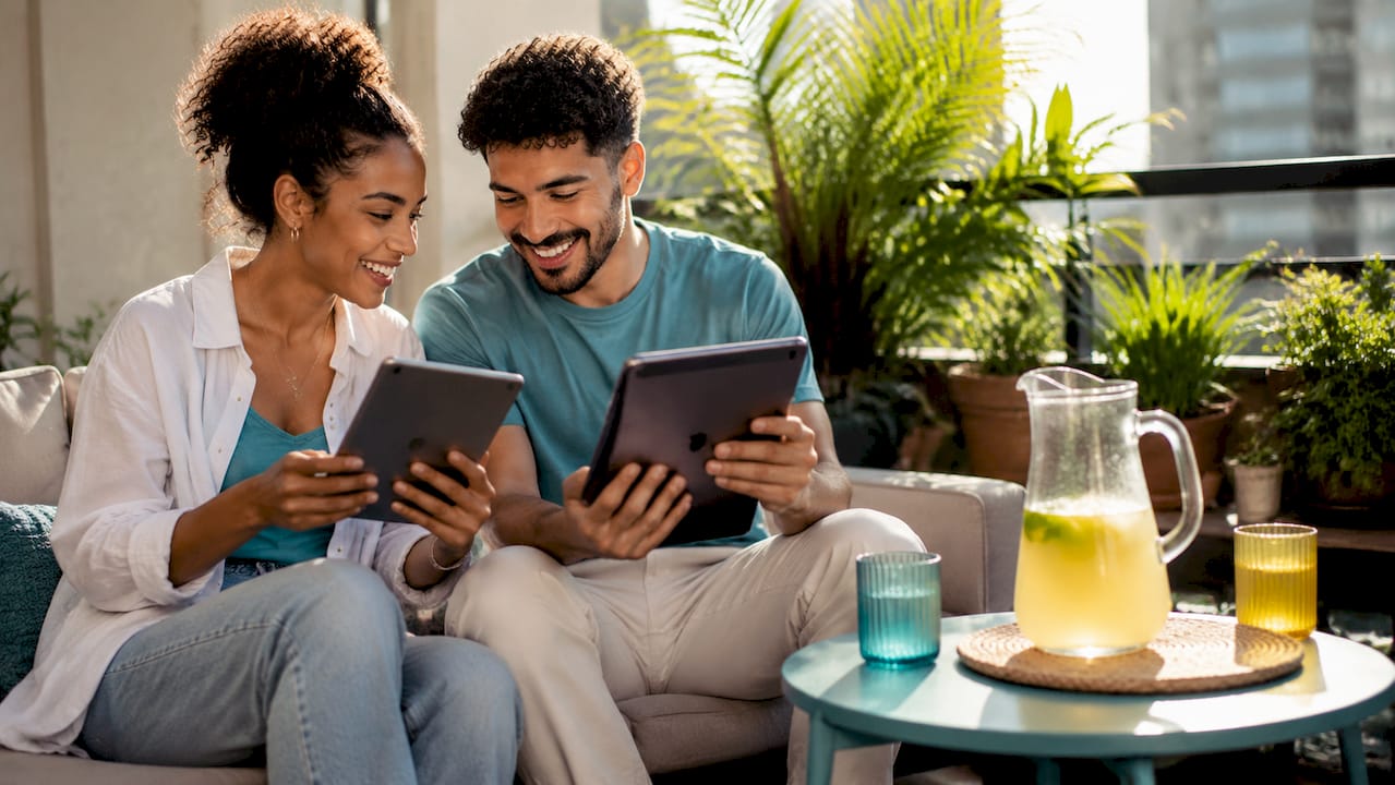 Couple coordinating wedding gift registry on tablets