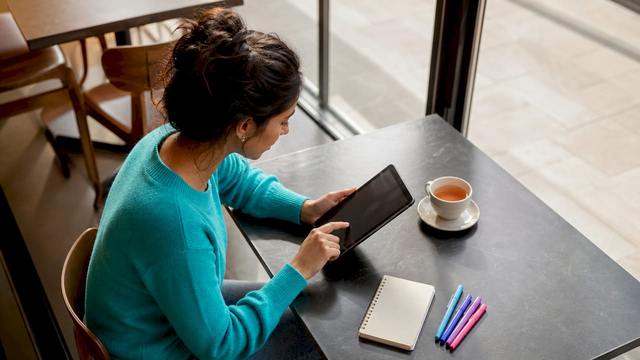 Woman sharing gift list on tablet at kitchen table
