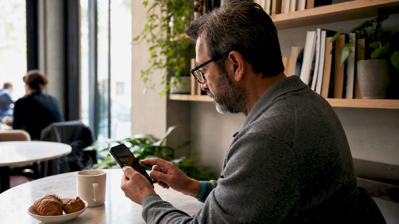 Hands using wishlist app on smartphone in café