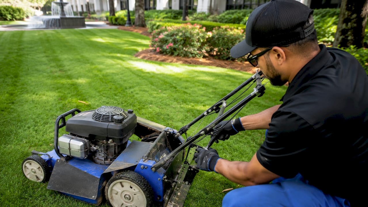 Commercial Lawn Care Best Practices for Property Managers 1 Technician adjusting mower height on commercial lawn