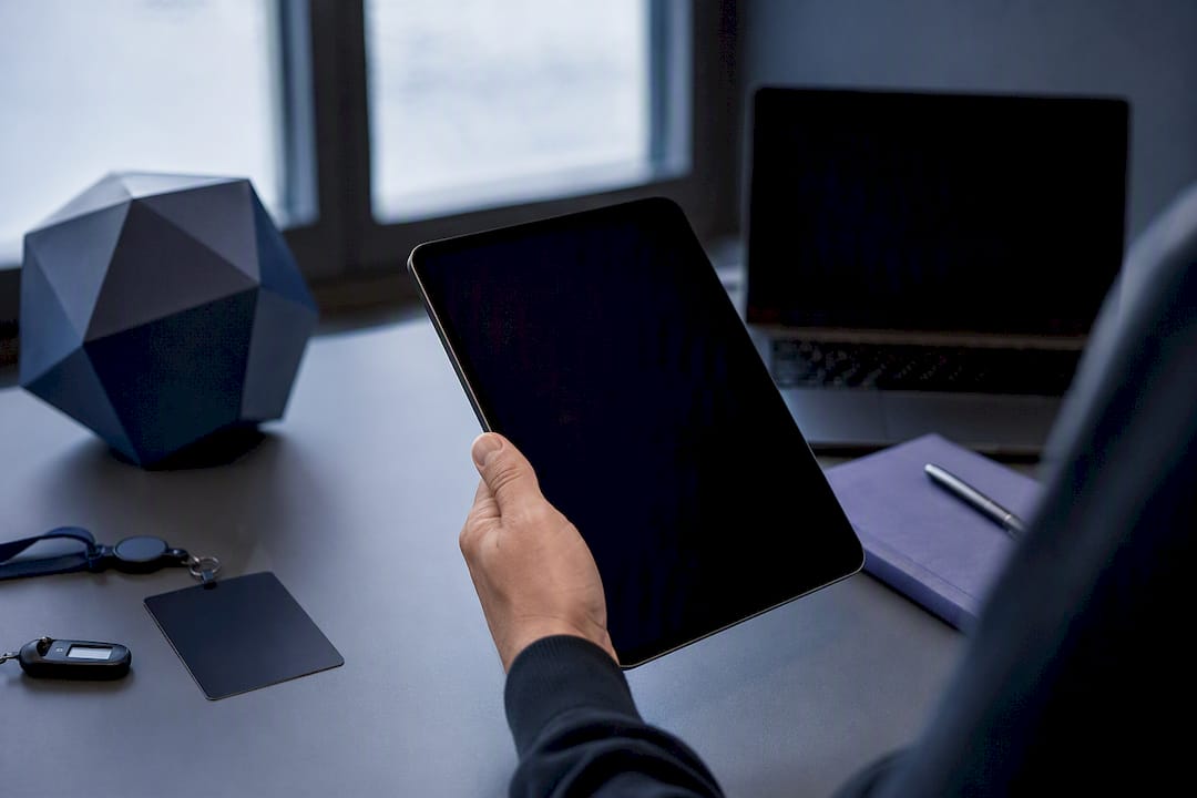 Hand holding dark tablet in compliance office