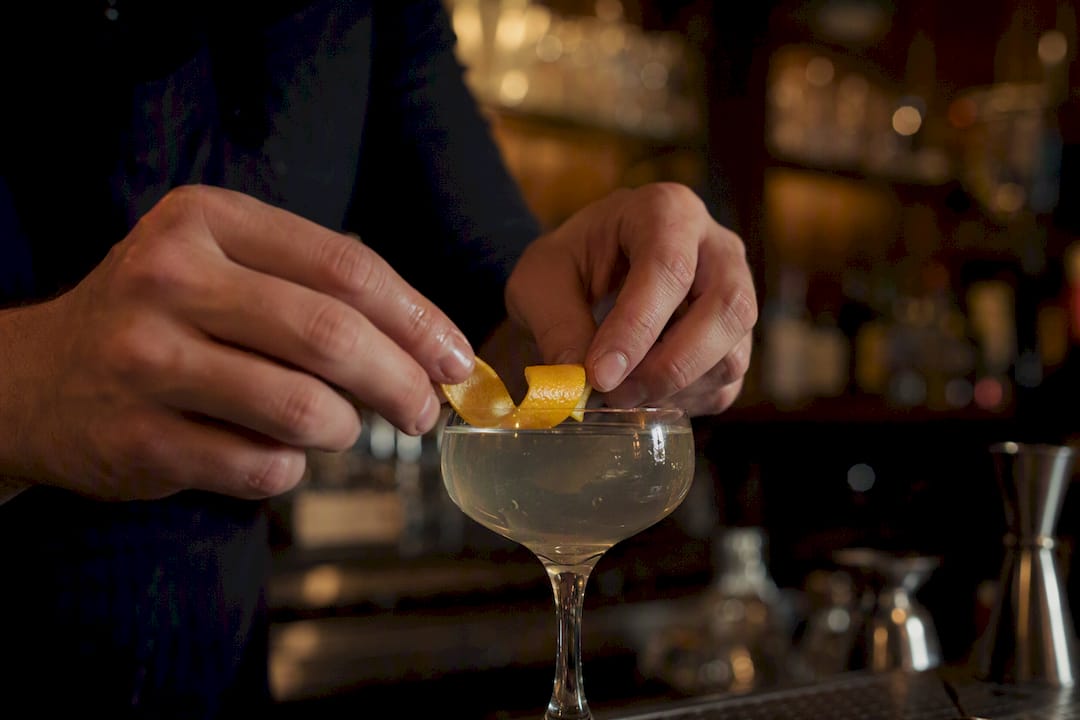 Barman ajoutant une garniture d'agrumes au cocktail