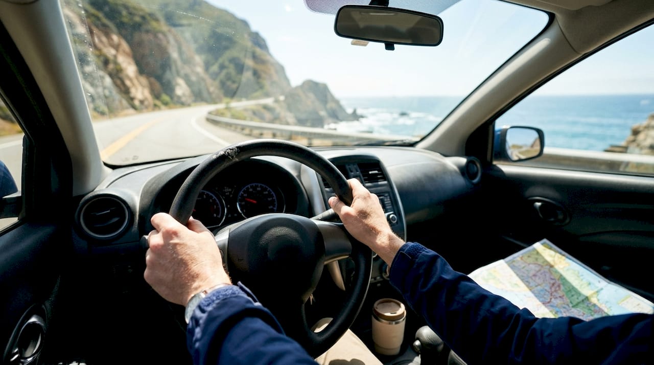 Driver's hands on steering wheel, car interior