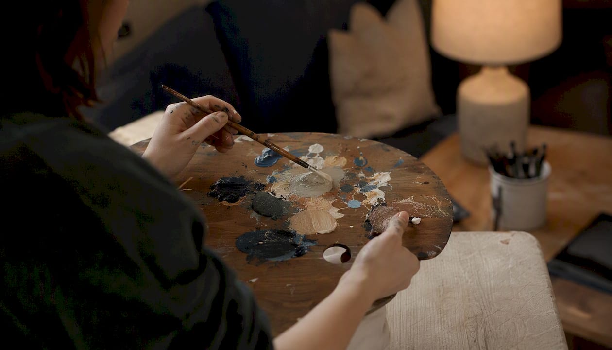 Hands mixing acrylic paint in a cozy art nook