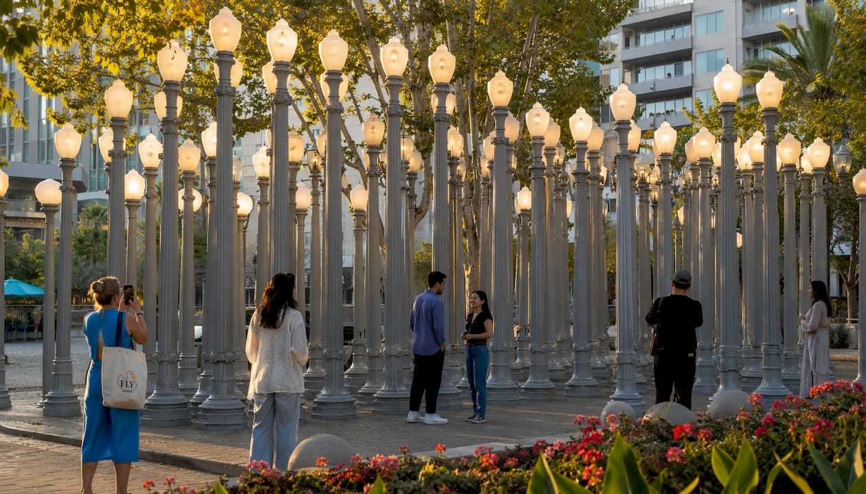 Visitors admiring outdoor lamp sculpture at dusk